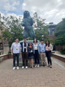 Taua at the conference, posing with lab mates in front of a bear statue.